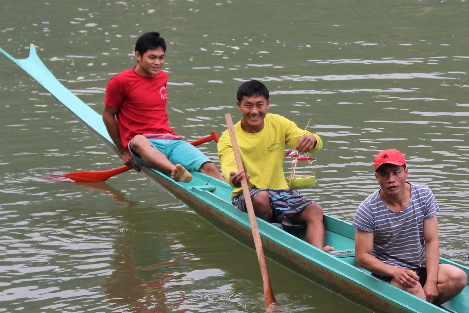 Laotians Village people on the boat holding tiny bamboo boats as good luck charm