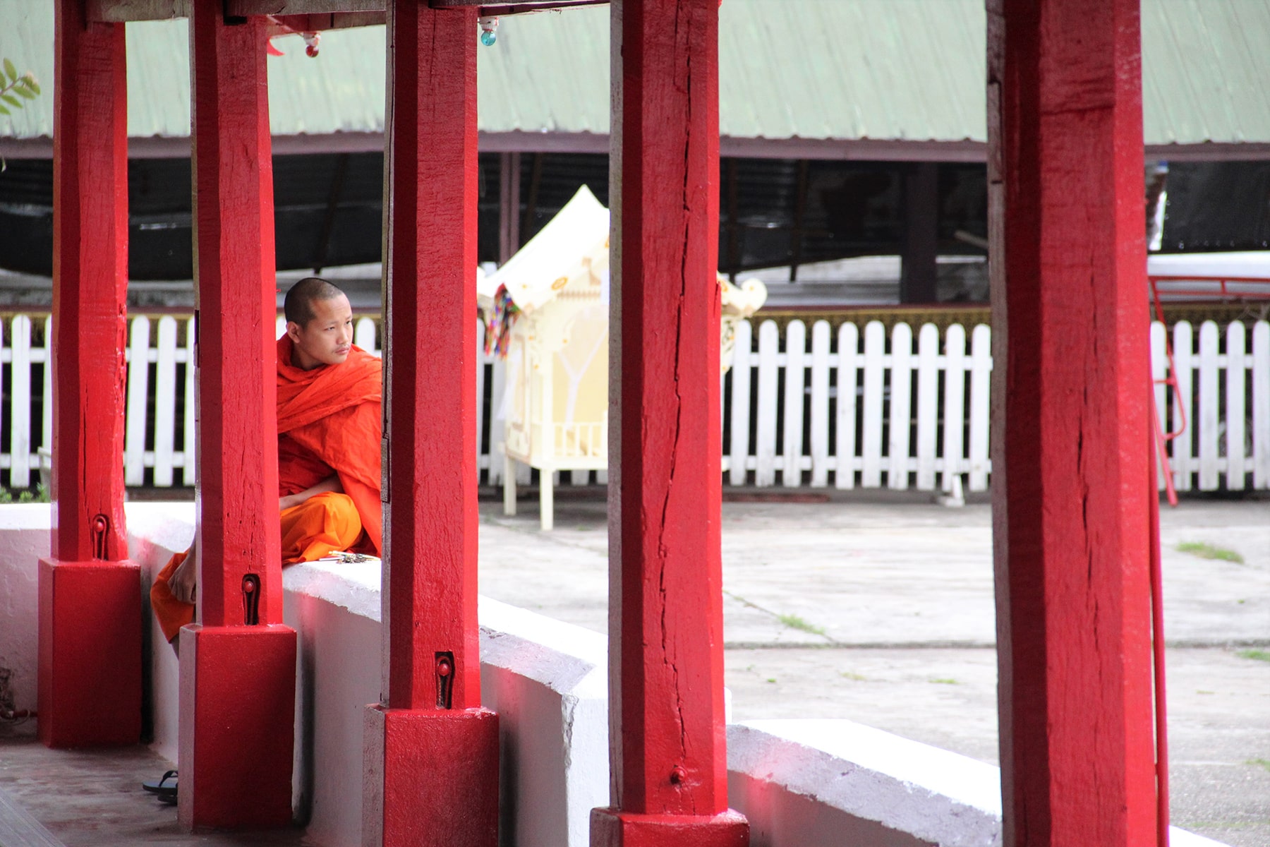 Moine entre les colonnes rouges du Wat Mai Suwannaphumaham à Luang Prabang, Laos