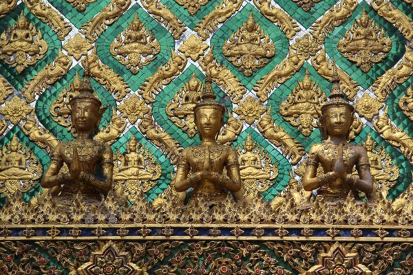 Persone che pregano come decori verdi e dorati del Palazzo reale di Bangkok