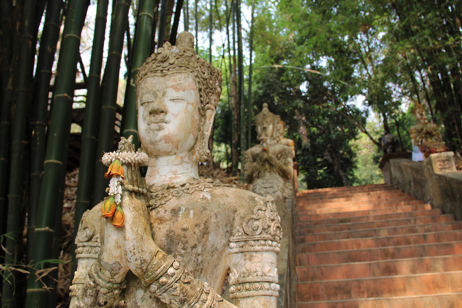 Statue priant avec des offrandes entre les mains dans le temple Wat Pha Lat à Chiang Mai