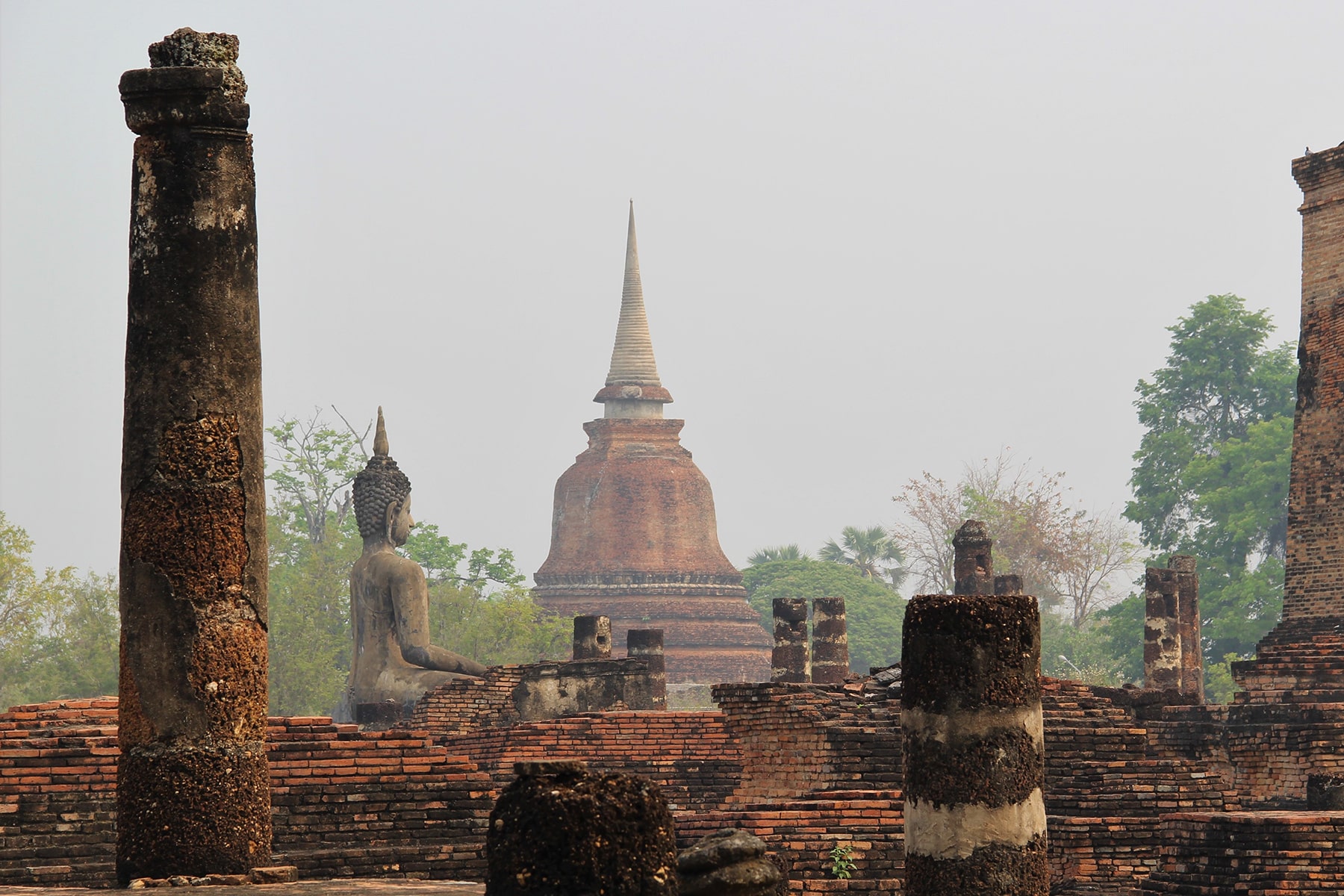 Colonnes, Statue de Bouddha et Stupa dans le brouillard dans le parc historique de Sukhothaï