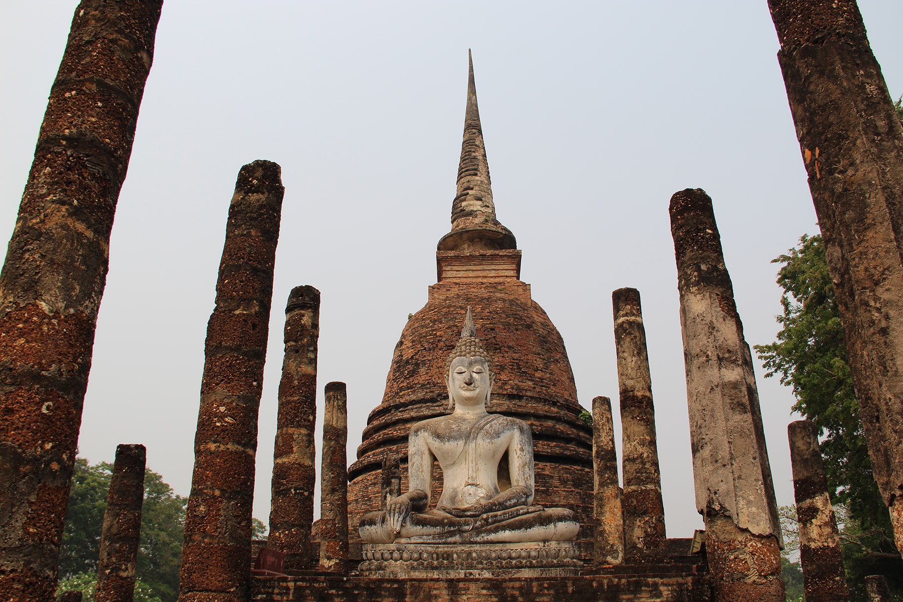 Bouddha et stupa entourés par des colonnes au parc historique de Sukhothaï