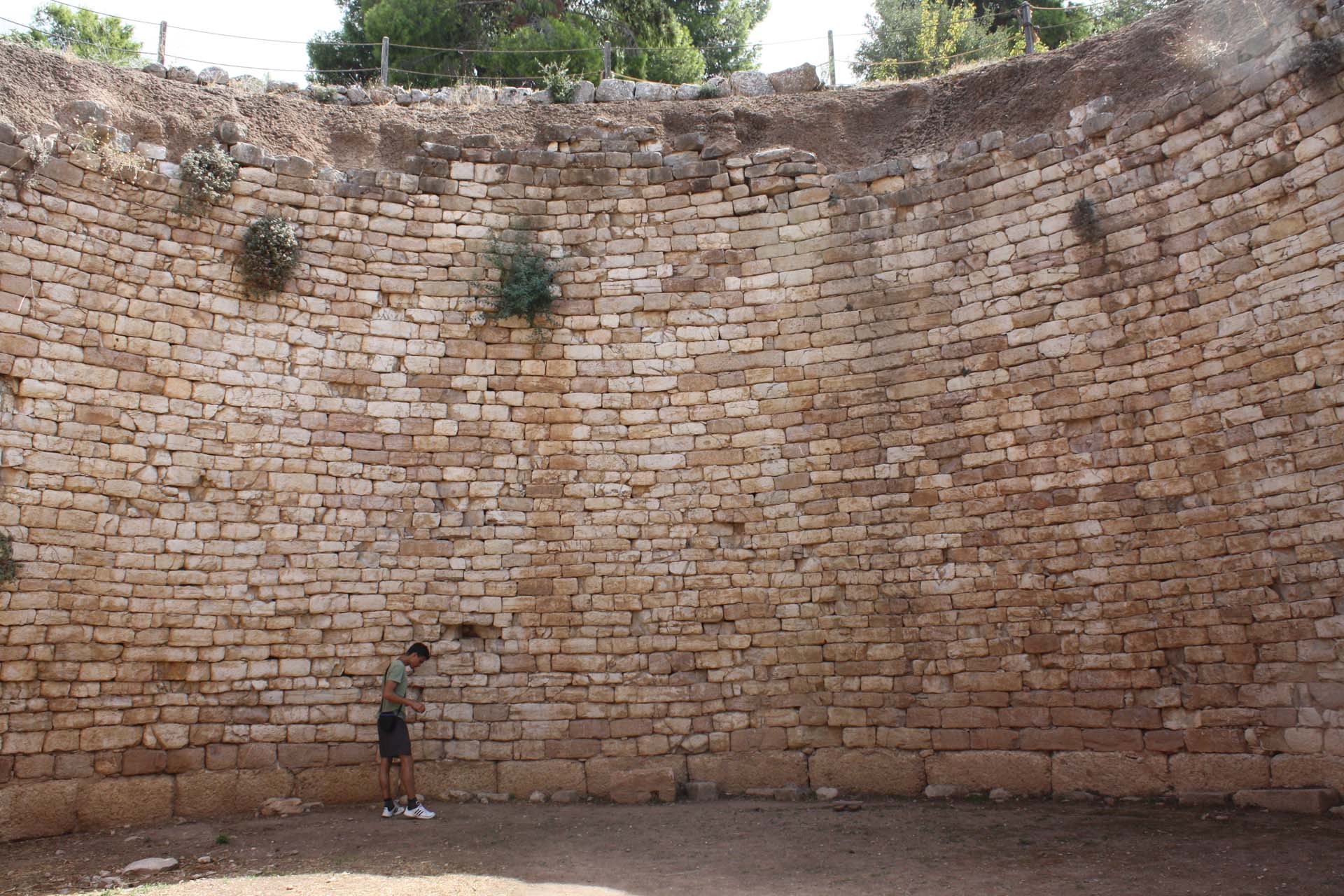 Man inside a tholos tomb in Mycenes, big round hole