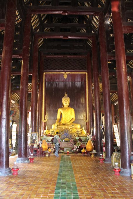 Interior of wooden Wat Phan Tao temple with golden Buddha in Chiang Mai