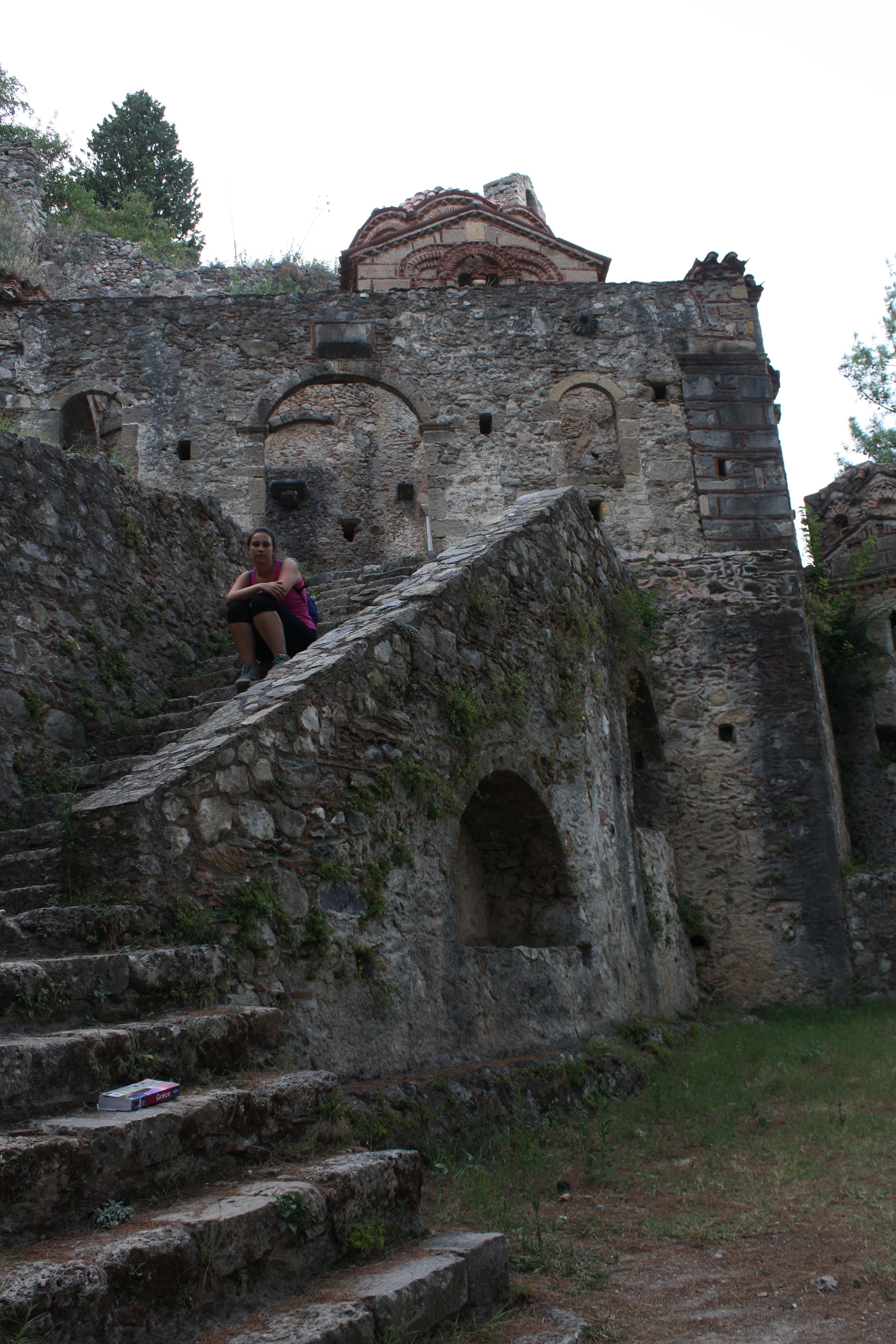 Woman sitting on stairs of the ruins of a monastery in Mystras